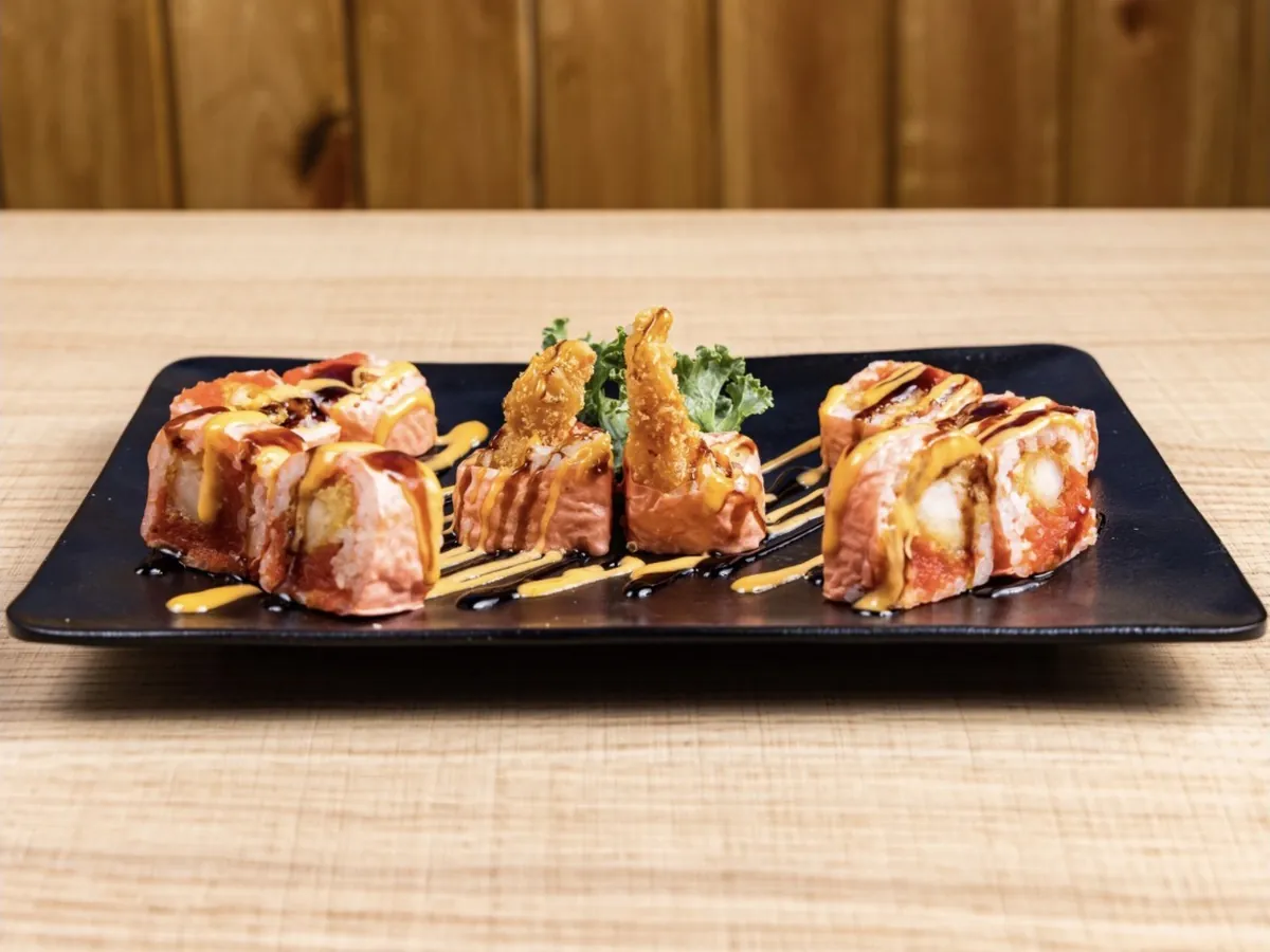 Amazing Bite Roll wrapped in orange soy paper with shrimp tempura tails standing at the centre