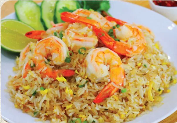 Shrimp fried rice plated with cucumber and lime