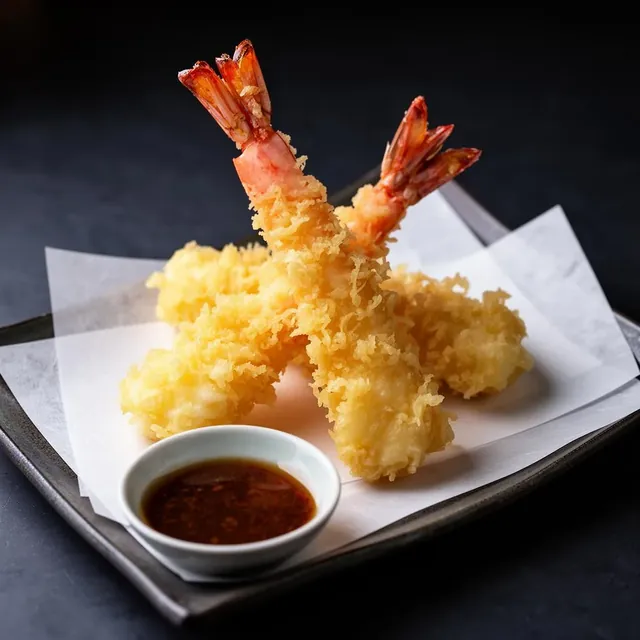 Crisp shrimp tempura served with dipping sauce on a white plate